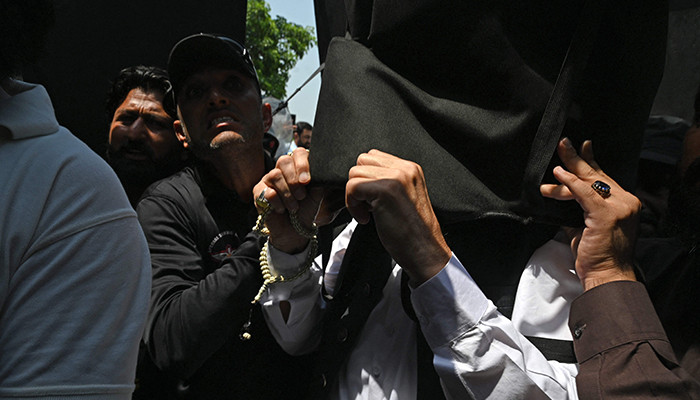 Former prime minister Imran Khan (right) holds a protective shield upon his arrival at the high court in Islamabad on June 8, 2023. — AFP