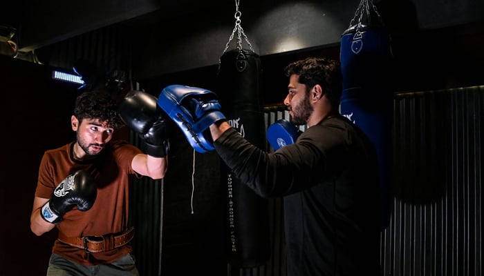 This picture taken on June 27, 2023 shows mountaineer Shehroze Kashif (L) training with coach Shamoz Khan at a gym in Lahore.