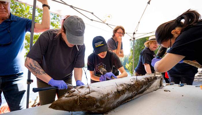 Carleton University PhD graduate, Krystin Lafond (2nd L), and other team members chisel frozen layers of lake bottom sediment from the outside of the probe brought from the depths of Crawford Lake near Milton, Ontario, Canada, April 12, 2023. — AFP