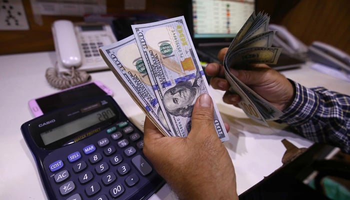 A man counting dollar bills in Karachi on March 2, 2023. — INP