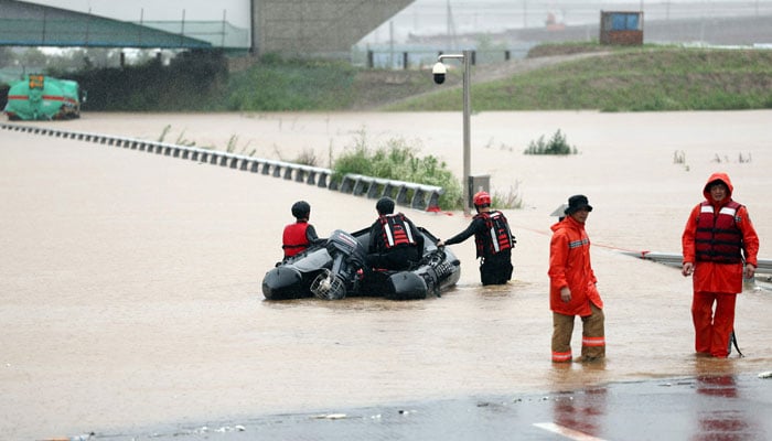 South Korean emergency workers search for survivors on a flooded road leading to an underground tunnel where about 19 cars were trapped by floodwaters after heavy rains in Cheongju on July 15, 2023. - AFP