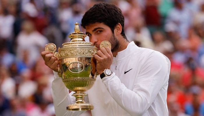 Carlos Alcaraz of Spain celebrates with the trophy after winning his final match against Novak Djokovic of Serbia at the All England Lawn Tennis and Croquet Club in London, Britain. reuters