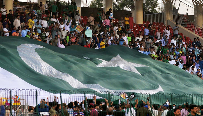 Pakistani spectators display a huge national flag at the Gaddafi Cricket Stadium in Lahore before the start of the third and final match between the World XI and Pakistan. — AFP/File