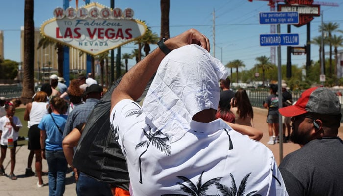 Satya Soviet Patnaik protects himself from the sun while waiting in line to take a photo at the historic Welcome to Las Vegas sign during a heat wave in Las Vegas. AFP/File