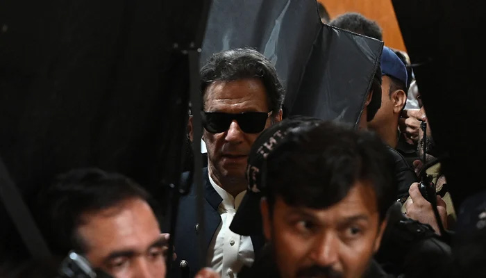 Security personnel with ballistic shields escort PTI Chairman Imran Khan as he leaves after appearing at the High Court in Lahore on May 19, 2023. — AFP