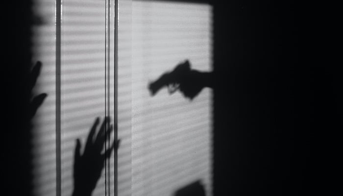 A representational image showing the silhouette of a person being held at gunpoint. — Unsplash