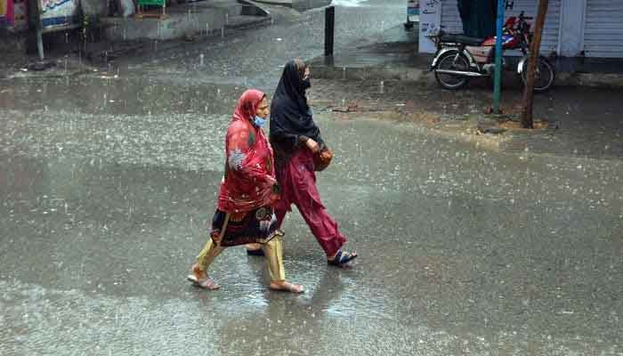 Women on their way at a road during heavy rain on March 24, 2023. — Online