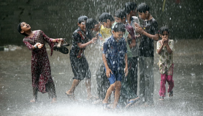 Children play in the rain in this undated file photo. — Reuters