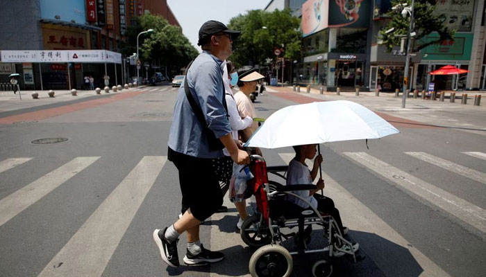 Pedestrians cross a road on a hot day amid an orange alert for heatwave, in Beijing, China June 16, 2023. — Reuters