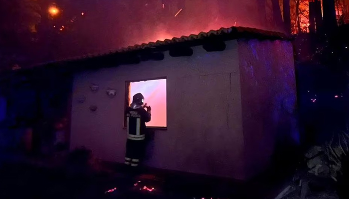 A firefighter checks a building as a wildfire burns near the Sicilian village of Curcuraci near Messina, Italy, July 25, 2023. — Reuters