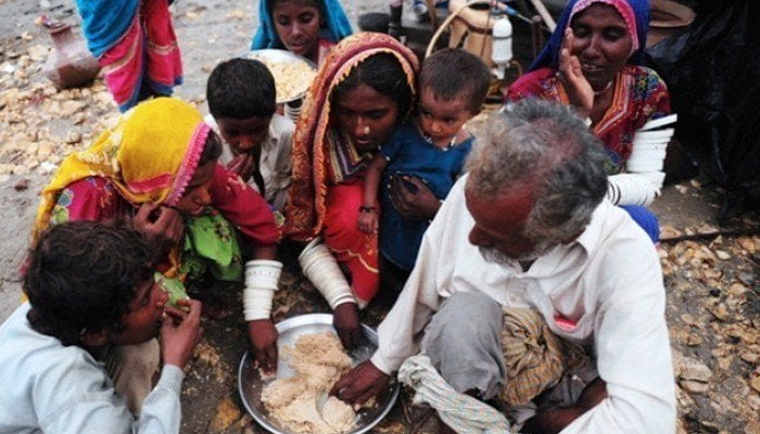 A family of eight shares a meal in the same plate. — AFP/File