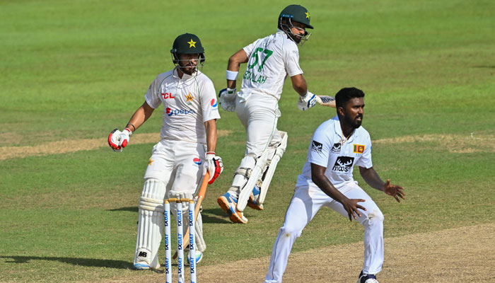 Pakistans Abdullah Shafique (centre) and Agha Salman (left) run between wickets as Sri Lankas Asitha Fernando watches during the third day of the second and final Test match between Pakistan and Sri Lanka at the Sinhalese Sports Club (SSC) ground in Colombo on July 26, 2023. — AFP