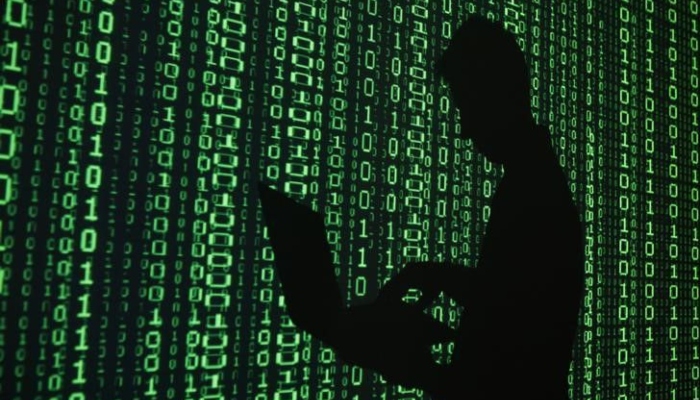 This photo shows a projection of binary code around the shadow of a man holding a laptop computer in an office. — Reuters/File