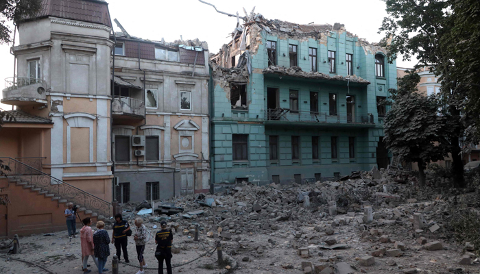 Local residents stand next to the buildings damaged as a result of a missile strike in Odesa on July 23, 2023. — AFP