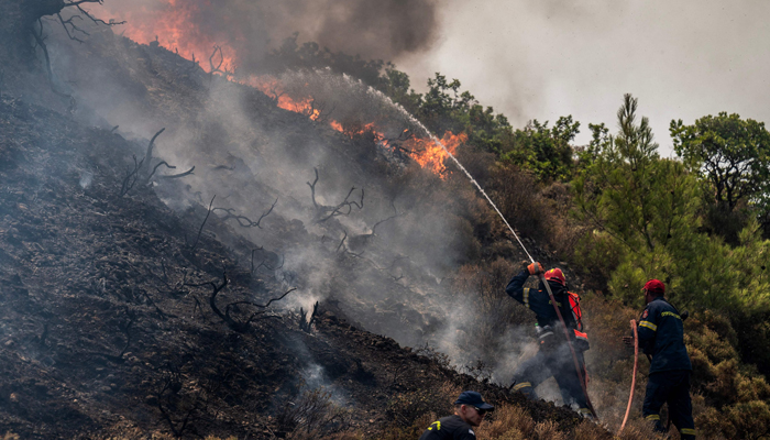 Firefighters use a hose as they take part in an operation against a fire near Vati, on the Greek Aegean island of Rhodes on July 26, 2023. — AFP