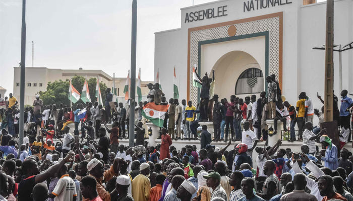 Supporters wave Nigerien flags as they rally in support of Nigers junta in front of the National Assembly in Niamey on July 30, 2023. — AFP