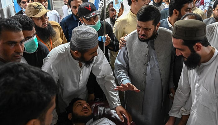Haji Ghulam Ali (second right), governor of KP province greets an injured man in a hospital in Peshawar on July 30, 2023. — AFP