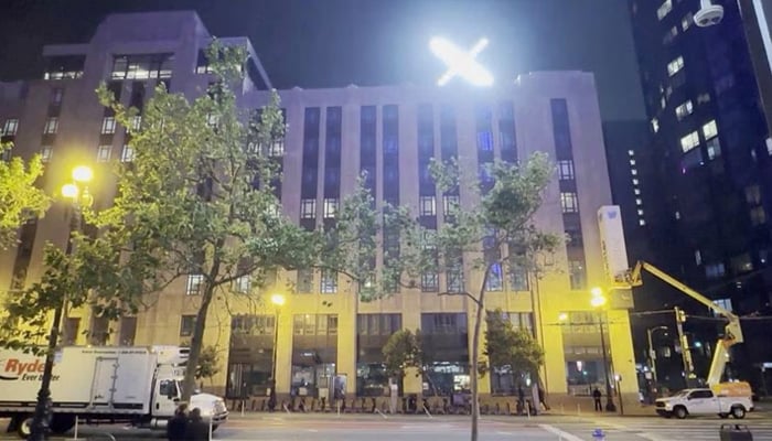 A crew works to remove the Twitter sign as an illuminated X logo is seen on top of the building in San Francisco, California, US, July 28, 2023, in this still obtained from a video. — Reuters