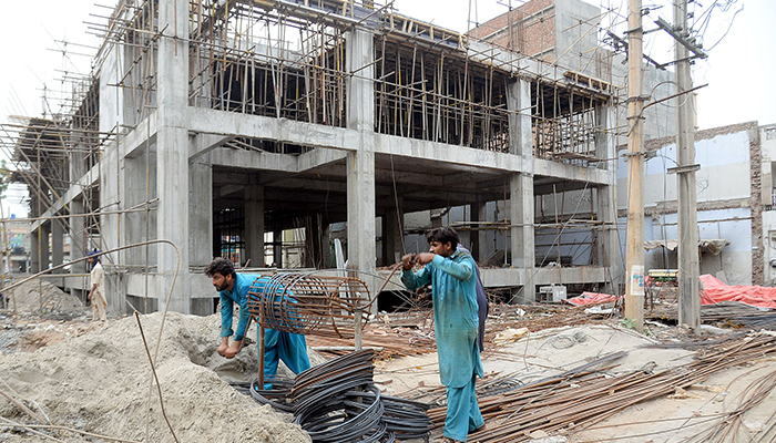 Labourers are working while constructing a building at Canal Road in Faisalabad on May 20, 2023. — Online