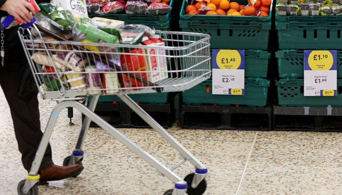 A person pushes a shopping cart next to the clubcard price branding inside a branch of a Tesco Extra Supermarket in London, Britain, February 10, 2022. — Reuters