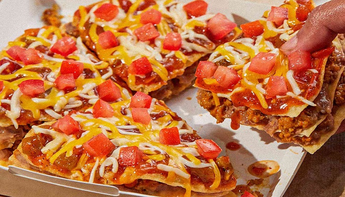 A representational image shows a pizza a person taking a piece of a pizza.—Taco Bell/Twitter