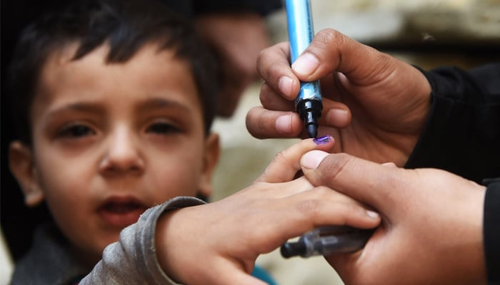 In this photograph taken on February 16, 2016, a health worker marks a childs finger after administering polio drops outside her house during a door-to-door polio immunisation campaign in Karachi. — AFP