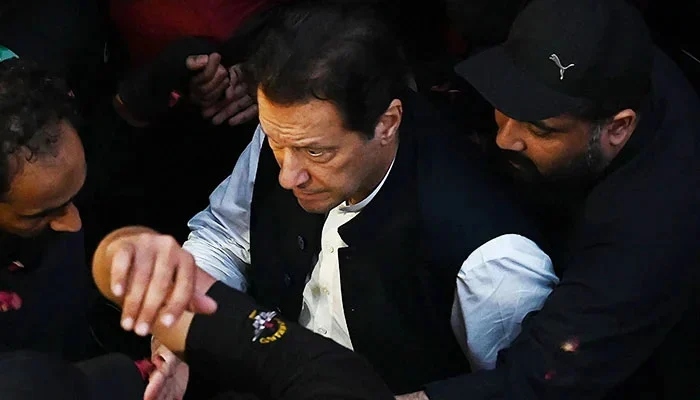 Security personnel escort former prime minister Imran Khan as he arrives to appear before the Lahore High Court on March 17, 2023. — AFP