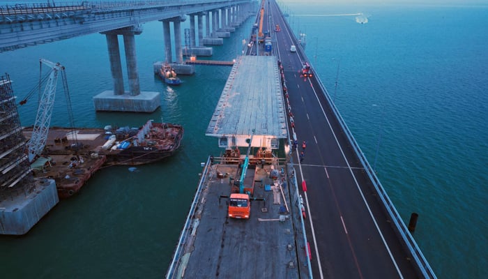 This photo shows an aerial view of repair works on damaged parts of the Kerch Bridge that links Crimea to Russia, which was hit by a blast on October 8, 2022. — AFP