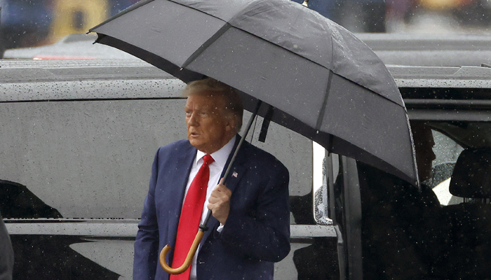 Former US President Donald Trump holds an umbrella as he arrives at Reagan National Airport following an arraignment in a Washington, D.C. court on August 3, 2023, in Arlington, Virginia. — AFP