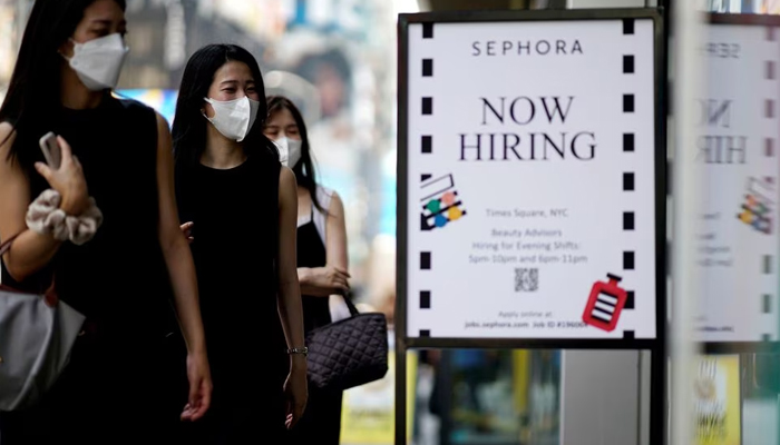 A sign advertising job openings is seen while people walk into the store in New York City, New York, US, August 6, 2021. — Reuters