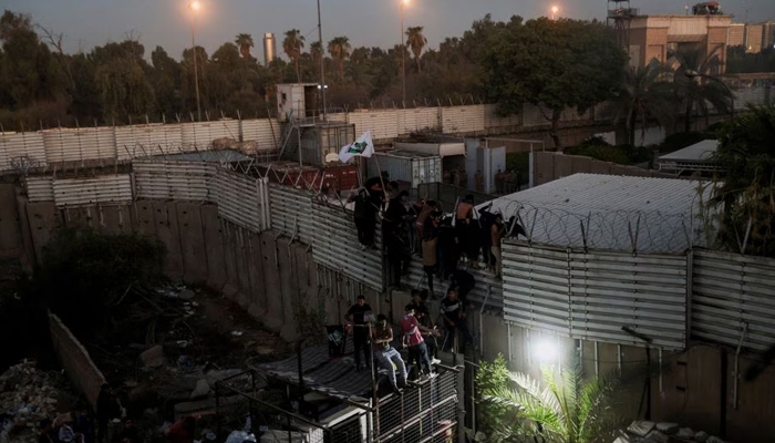 Protesters climb a fence as they gather near the Swedish embassy in Baghdad hours after the embassy was stormed and set on fire ahead of an expected Koran burning in Stockholm, in Baghdad, Iraq, July 20, 2023. — Reuters