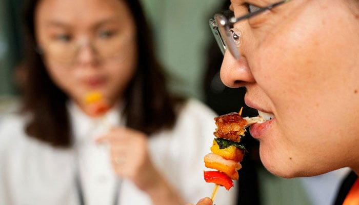 A woman tastes lab-grown meat served by CellX at an event to mark the opening of the cultivated meat companys pilot production facility in Shanghai, China August 9, 2023. — Reuters