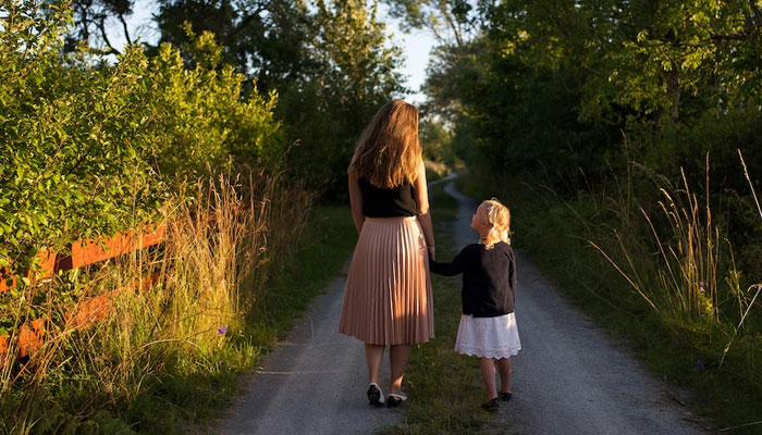 A representational image showing a woman with a young girl on a wooden way. — Unsplash/File