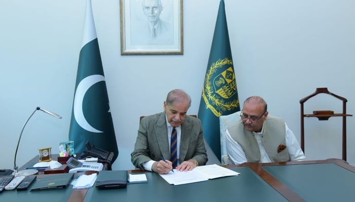 PM Shehbaz Sharif signs the summary after the selection of Senator Anwaar-ul-Haq Kakr as caretaker prime minister. — PM Office