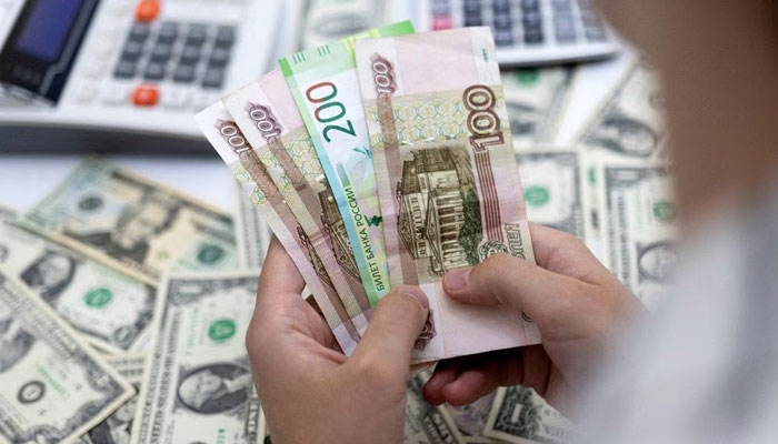 A woman holds Russian Roubles in front of US Dollar banknotes in this illustration taken May 30, 2022. — Reuters/File