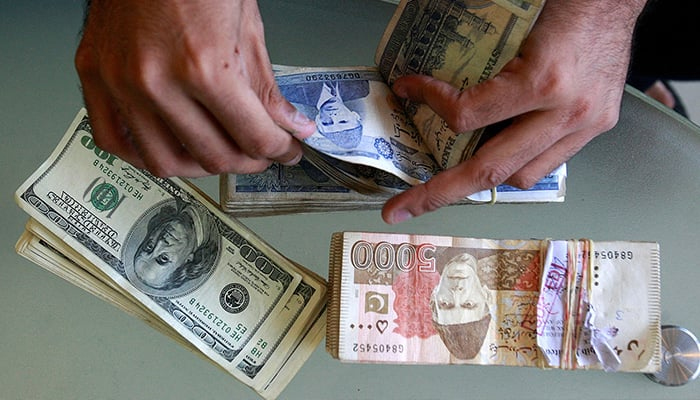 A currency dealer counts Pakistani rupees and US dollars at his shop in Karachi. — Reuters/File