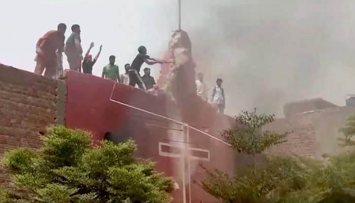 A protester standing on the roof of a church vandalises the building structure in Jaranwala, Faisalabad August 16, 2023 in this screengrab obtained from a video by Reuters TV.