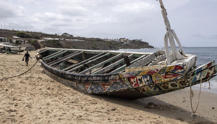 A man walks past a beached pirogue in which 17 migrants lost their lives after it capsized off the coast of Dakar in mid-July, allegedly on its way to the Canary Islands, Dakar, Senegal. — AFP/File