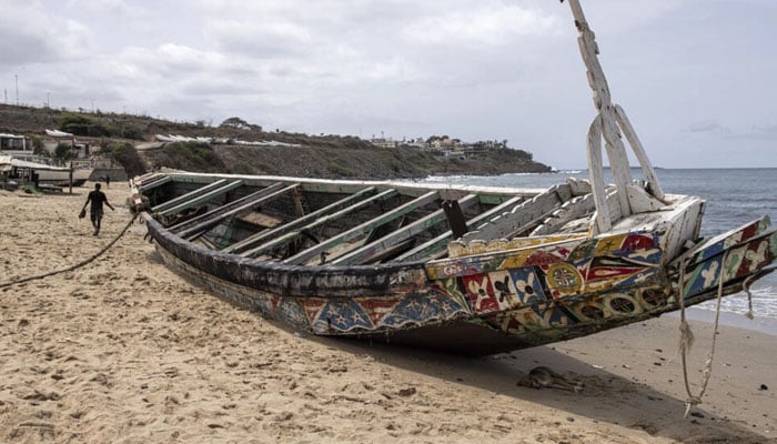 A man walks past a beached pirogue in which 17 migrants lost their lives after it capsized off the coast of Dakar in mid-July, allegedly on its way to the Canary Islands, Dakar, Senegal. — AFP/File