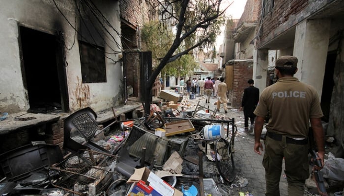 A police officer walks past the belongings of the residents along a street in a Christian neighbourhood, a day after the church buildings and houses were vandalised by protesters in Jaranwala, August 17, 2023. — Reuters