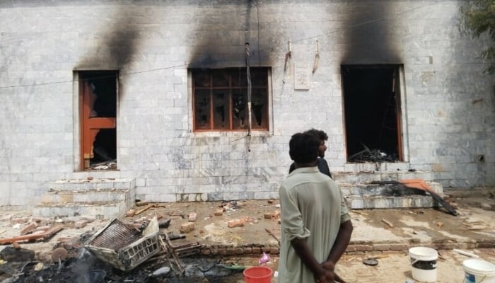 Men study the damaage to a building after the riot in Jaranwala on August 17, 2023 — AFP