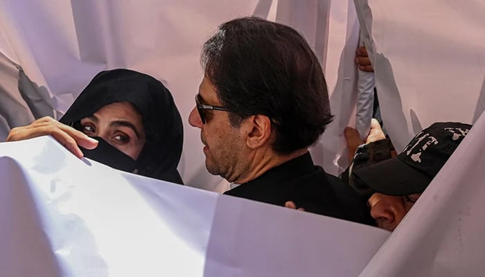 Former prime minister Imran Khan (centre) with his wife Bushra Bibi arrive to appear at a high court in Lahore on May 15, 2023. — AFP
