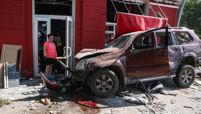 A local resident stands next to a damaged car at the site of a missile strike in Chernihiv, on August 19, 2023. — AFP