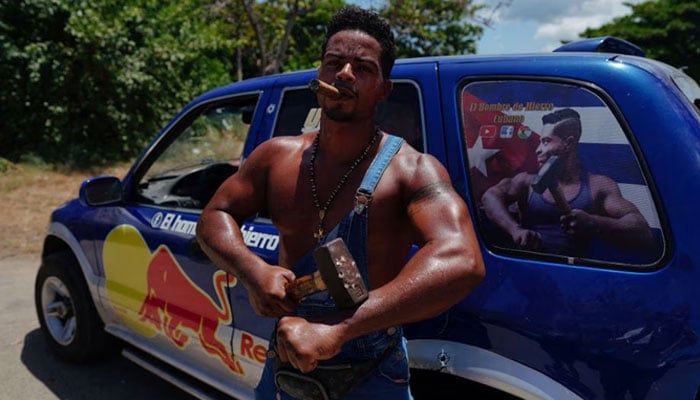 Cubas Ironman Lino Tomasen poses beside his car before performing to beachgoers in Guanabo, Cuba, August 9, 2023.—Reuters