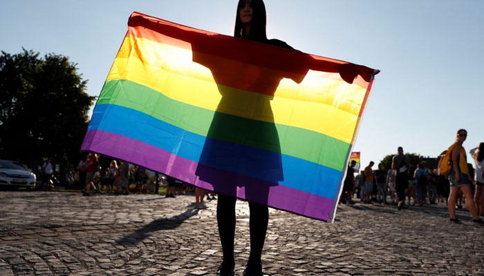 The image shows a woman carrying the rainbow pride flag. — Reuters