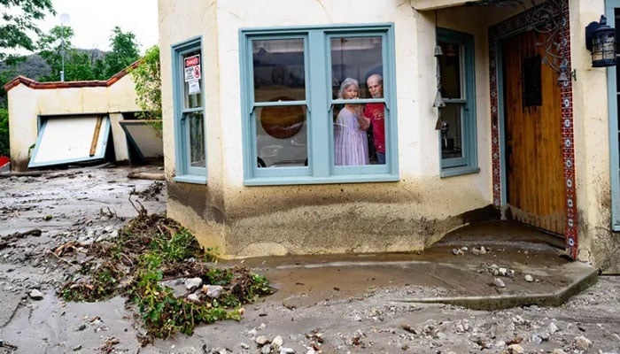Residents trapped in their home peer out a window while waiting for help in Yucaipa, California on Aug. 21, 2023. Tropical Storm Hilary drenched Southern California with record rainfall, shutting down schools, roads, and businesses before edging in on Nevada on Aug. 21, 2023. California Governor Gavin Newsom had declared a state of emergency over much of the typically dry area, where flash flood warnings remained in effect until this morning. AFP