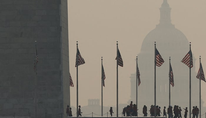 Tourists walk around the base of the Washington Monument as wildfire smoke casts a haze off the US Capitol on the National Mall on June 07, 2023, in Washington, DC. — AFP