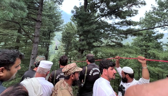 This handout photograph taken on August 22, 2023 and released by the Inter Service Public Relation (ISPR) shows an army soldier (top) rescueing a student survivor, who was trapped in a cable car following an incident, in Battagram. —AFP