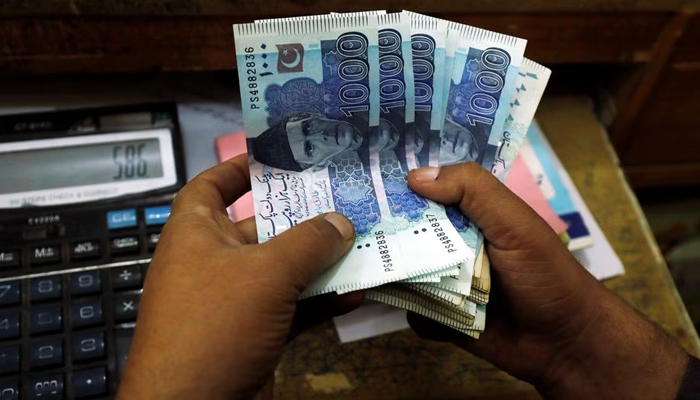 A trader counts Pakistani rupee notes at a currency exchange booth in Peshawar, Pakistan December 3, 2018.— Reuters