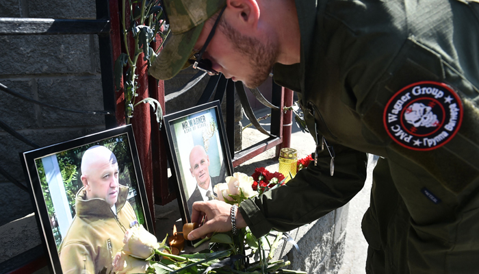 A member of Wagner pays tribute to Yevgeny Prigozhin (L) and Dmitry Utkin at the makeshift memorial in front of the Wagner office in Novosibirsk, on August 24, 2023. — AFP